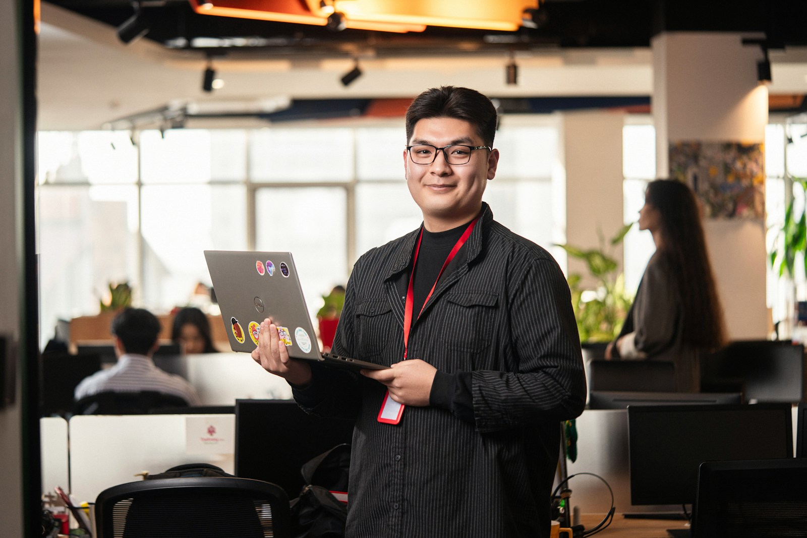 Man holding a laptop in a modern office setting.