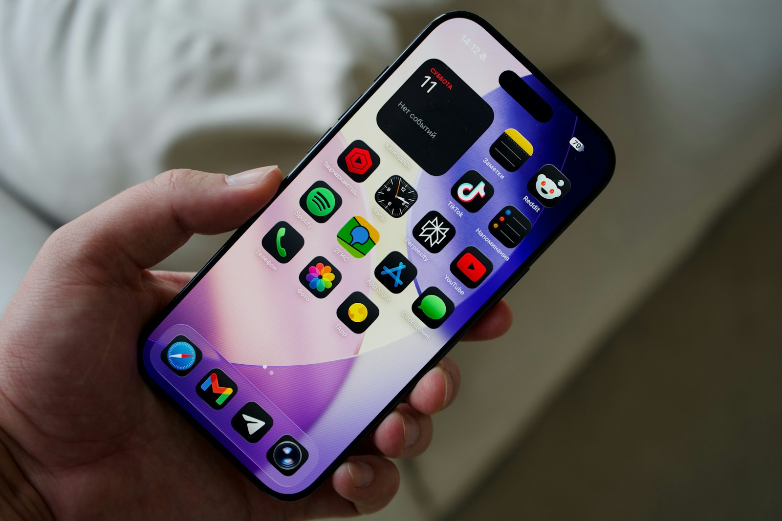 Hand holding a smartphone with colorful app icons.