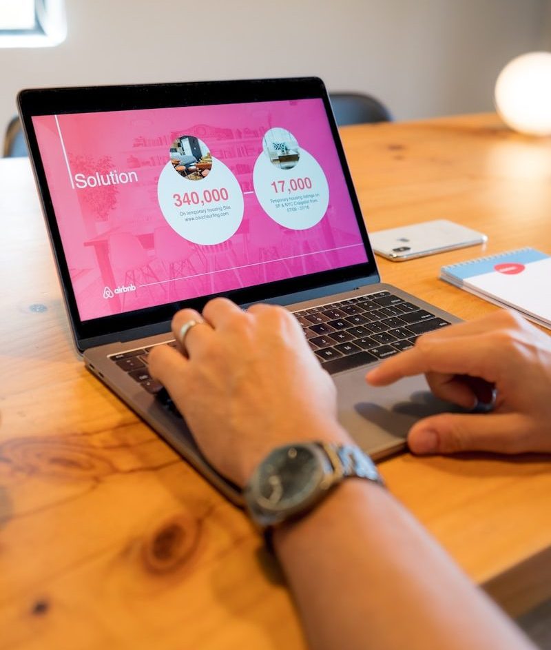person using macbook pro on brown wooden table