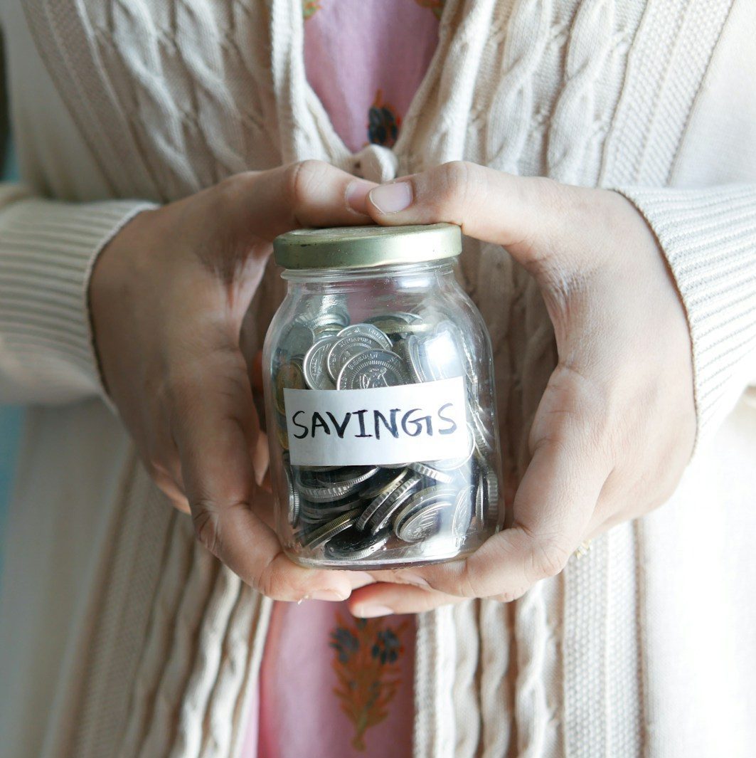 a woman holding a jar with savings written on it